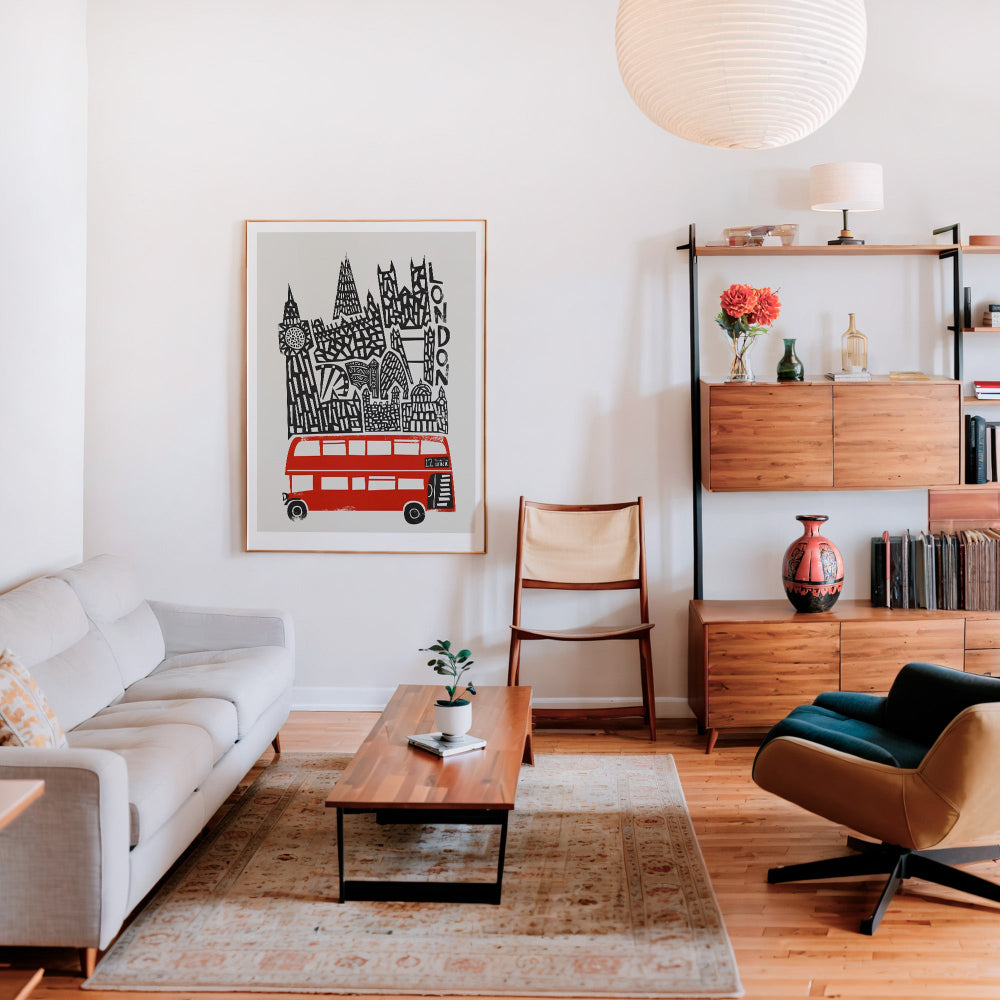 Red London bus illustration framed and displayed in a modern interior, adding graphic energy and city charm to a warm, neutral-toned lounge.
