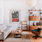 Red London bus illustration framed and displayed in a modern interior, adding graphic energy and city charm to a warm, neutral-toned lounge.
