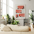 London bus wall art styled in a bright, leafy lounge space, complementing the neutral palette with its bold red accents and joyful mid-century layout.
