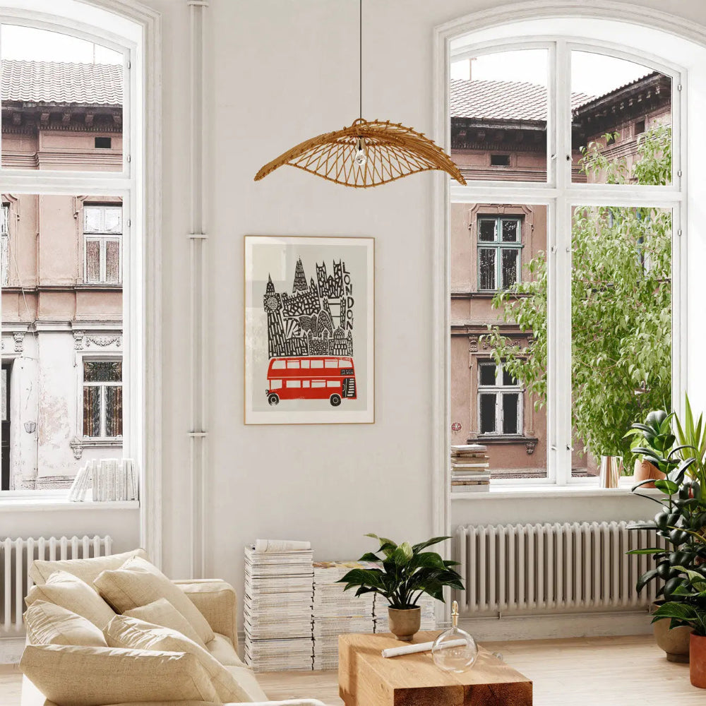 Stylised London bus art print hanging in a bright living space, showcasing the capital’s landmarks and mid-century type alongside a vivid pop of red in the classic bus.
