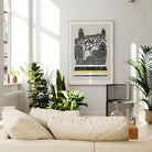Framed LA art print hanging in a bright living room, blending modern cityscape artwork with calm, neutral home decor and leafy indoor plants.