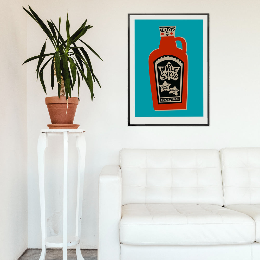 Maple Syrup artwork framed on a white wall beside a tall potted plant and modern bench.