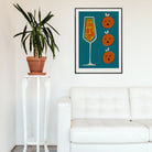 Mimosa cocktail poster framed above a white sofa and houseplant in a crisp, minimal interior.