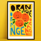 Vibrant orange print with smiling fruit faces and bold hand-cut typography.