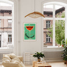 The framed print hung in a soft-toned, leafy living space where the mint background and graphic red-orange create a bold visual contrast.
