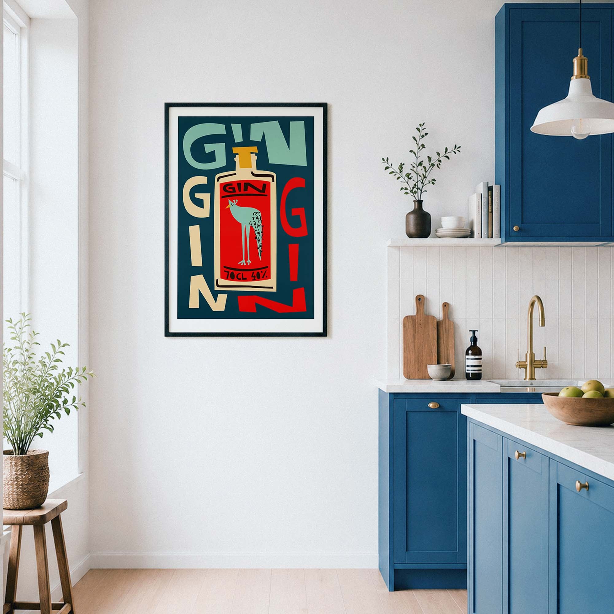 A framed vertical art print featuring a stylized red and cream gin bottle with the word 'GIN' in large block letters, displayed on a white wall in a modern kitchen setting with blue cabinets.