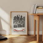 The Portland art print propped on a floor against a white wall, with sunlight casting long shadows across the classic architectural lines.