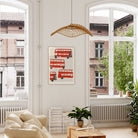 Mid-century red bus illustration framed and hanging in a tall, airy room with arched windows, adding a bold hit of colour to the calming neutral décor.
