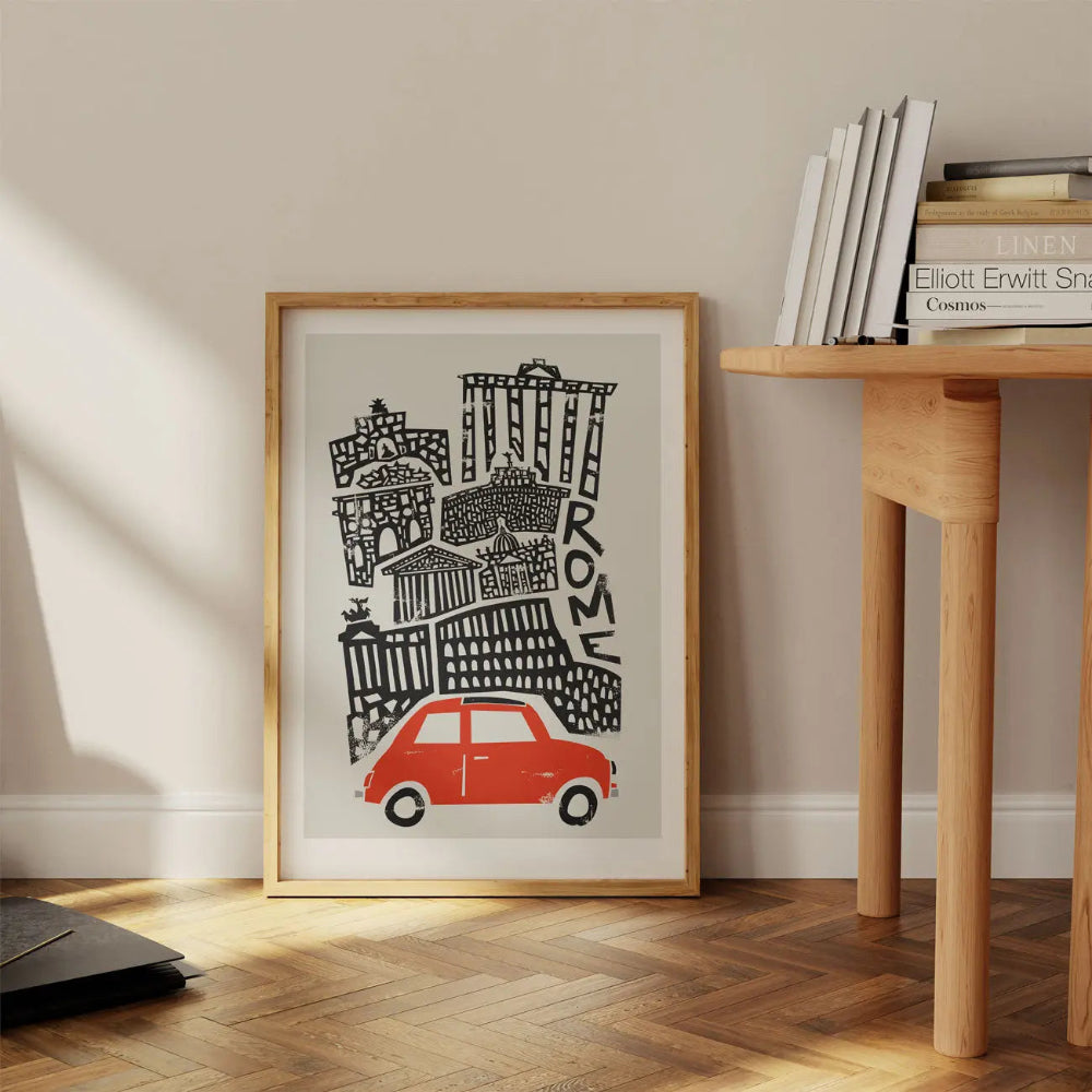 Framed Rome city print with red Fiat resting on the floor near a wooden desk—mid-century line work meets warm nostalgic charm in a modern space.
