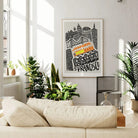 The San Francisco city print framed and displayed in a light-filled lounge, with soft neutral décor and leafy greens adding warmth to the urban energy of the artwork.
