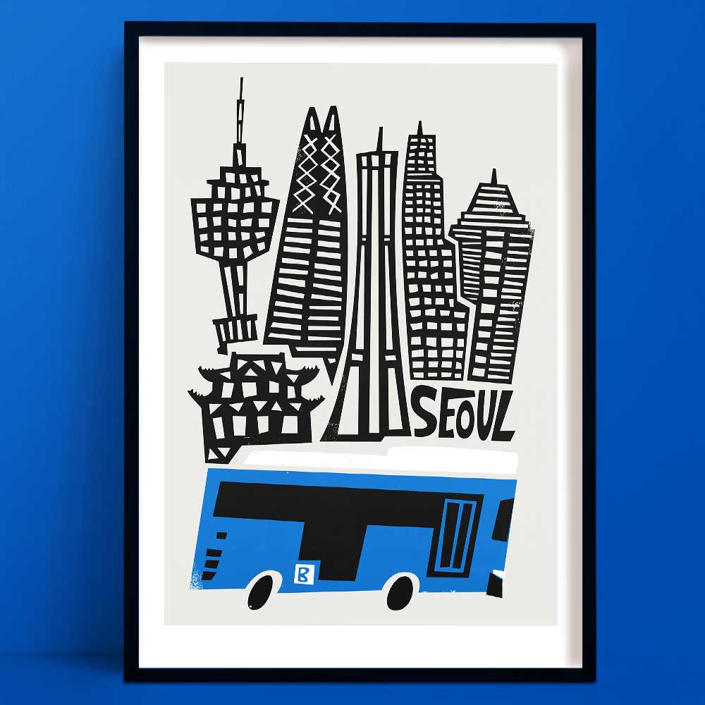 Seoul city art print featuring bold black-and-white architectural silhouettes above a stylised blue city bus, framed on cobalt wall.