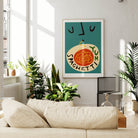 The Spaghetti Yum print on a teal wall in a sunlit living room, adding warmth and personality to the modern furnishings and leafy green decor.
