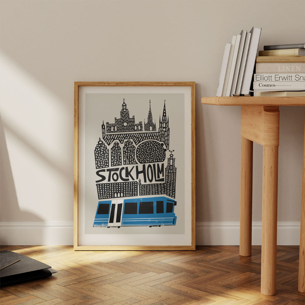 The Stockholm city print propped casually against a pale wall beside a wooden desk, creating a relaxed Scandinavian interior vibe.