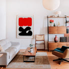 A living room scene with the Sundown print taking centre stage on a red accent wall, its abstract simplicity commanding attention amid cosy, eclectic decor.
