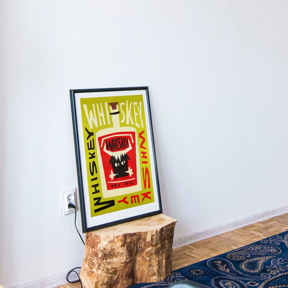 Whiskey poster resting casually against a white wall on a rustic tree stump base in a relaxed, boho interior.