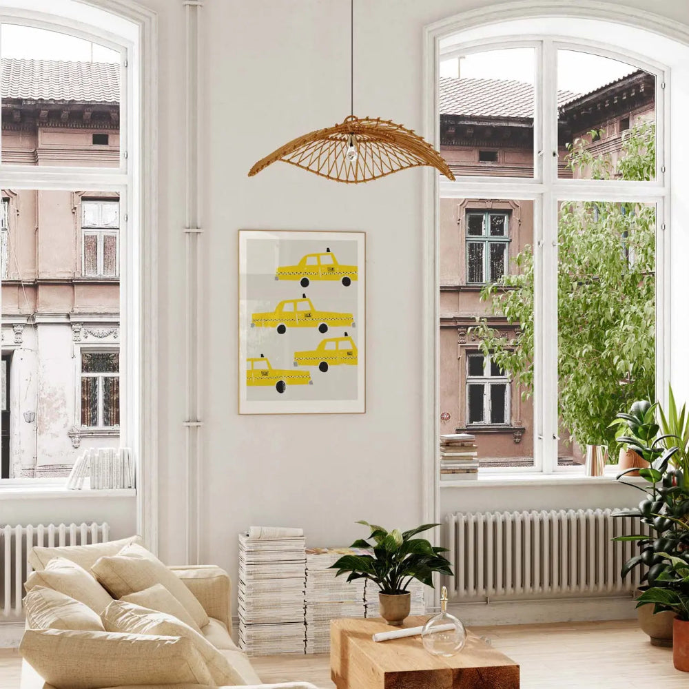 The taxi art print hung in a stylish, sun-filled room with wooden flooring and leafy plants, adding a cheerful splash of colour and a nostalgic city vibe.
