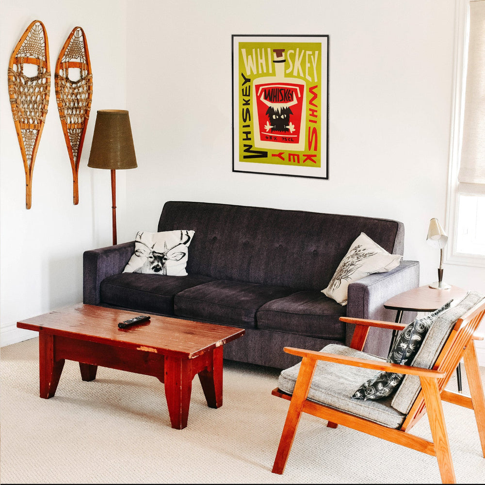 Whiskey print framed above a dark sofa in a retro living space with skis on the wall and vintage wood accents.